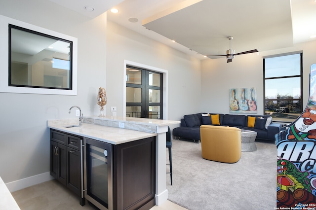 living room with sink, light colored carpet, ceiling fan, and wine cooler