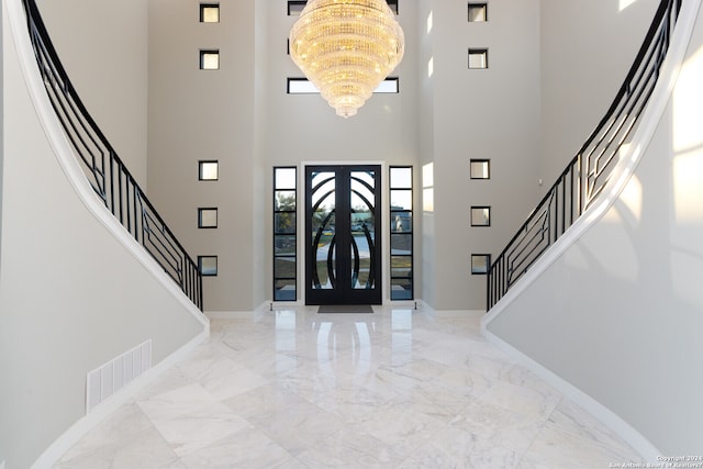 foyer featuring a chandelier, light tile floors, a high ceiling, and french doors