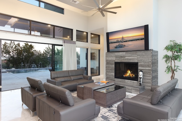 living room with ceiling fan, a towering ceiling, and light tile flooring