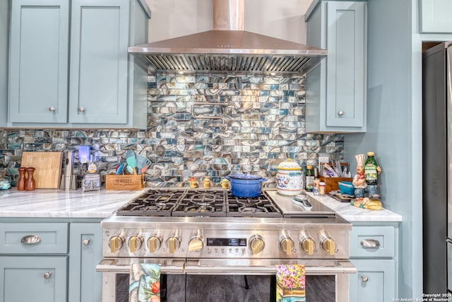 kitchen featuring light stone countertops, appliances with stainless steel finishes, tasteful backsplash, and wall chimney exhaust hood