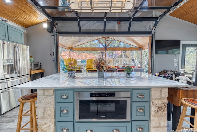 kitchen featuring vaulted ceiling, wood ceiling, appliances with stainless steel finishes, and light stone counters