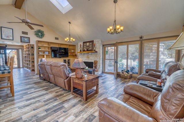 living room featuring a skylight, a stone fireplace, hardwood / wood-style flooring, and ceiling fan with notable chandelier