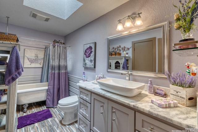 full bathroom featuring vanity, a skylight, shower / bath combo with shower curtain, and toilet