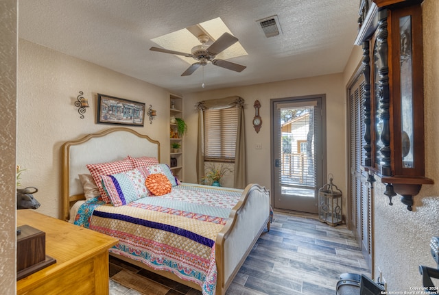 bedroom with a textured ceiling, ceiling fan, and hardwood / wood-style flooring