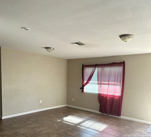 275 E Hutchins St, La Pryor, TX 78872 - unfurnished room with a textured ceiling and dark tile floors