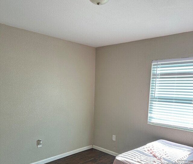 275 E Hutchins St, La Pryor, TX 78872 - bedroom featuring multiple windows and dark wood-type flooring