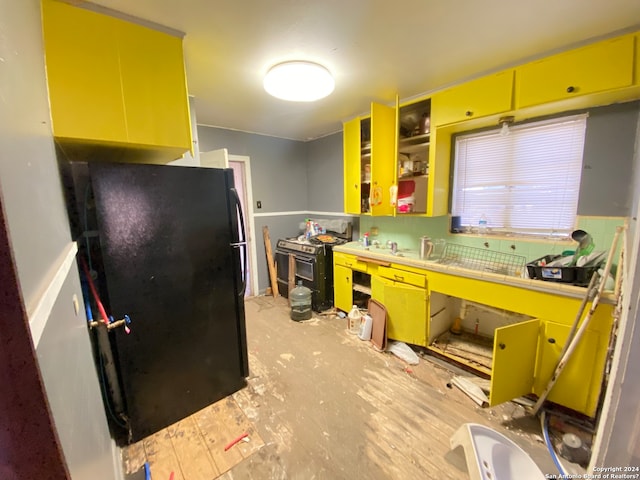 kitchen with black refrigerator and light hardwood / wood-style floors