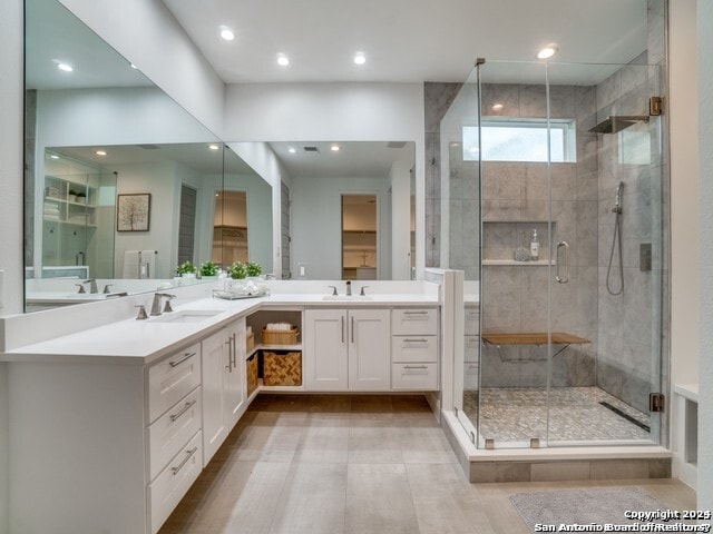 bathroom with dual vanity and an enclosed shower