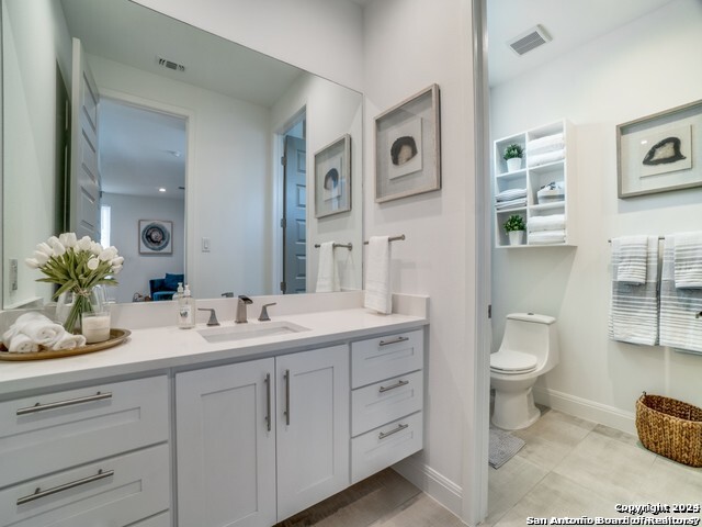bathroom with toilet, tile floors, and vanity