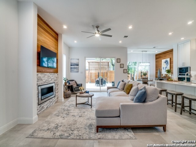 living room with light tile floors, ceiling fan with notable chandelier, and a fireplace