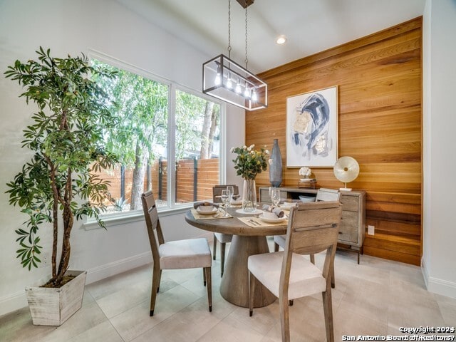 tiled dining area with wood walls and a chandelier