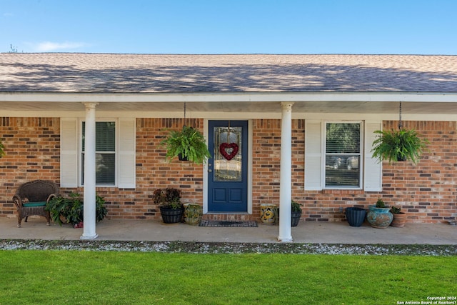 entrance to property featuring a lawn and a porch