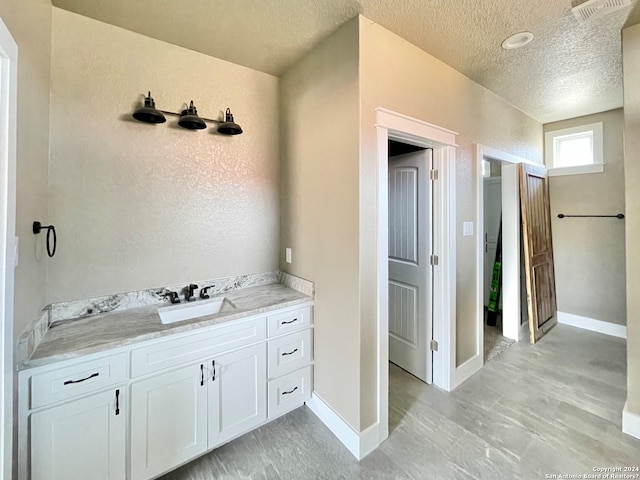 bathroom with vanity, a textured ceiling, and tile flooring