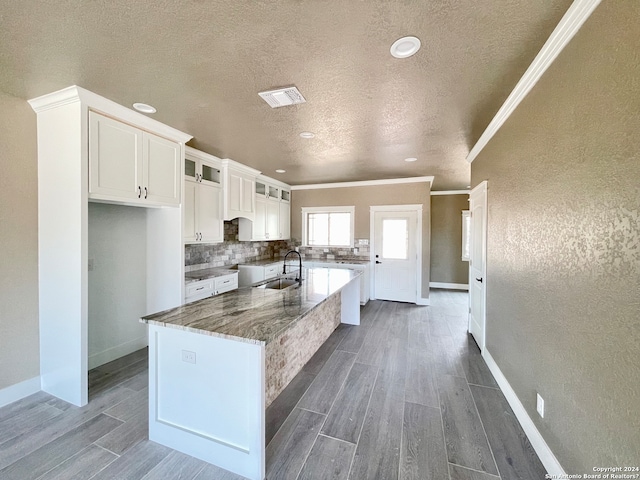 kitchen with sink, crown molding, backsplash, stone countertops, and white cabinetry