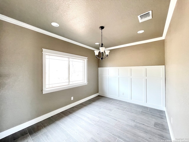 unfurnished room with a notable chandelier, a textured ceiling, and ornamental molding