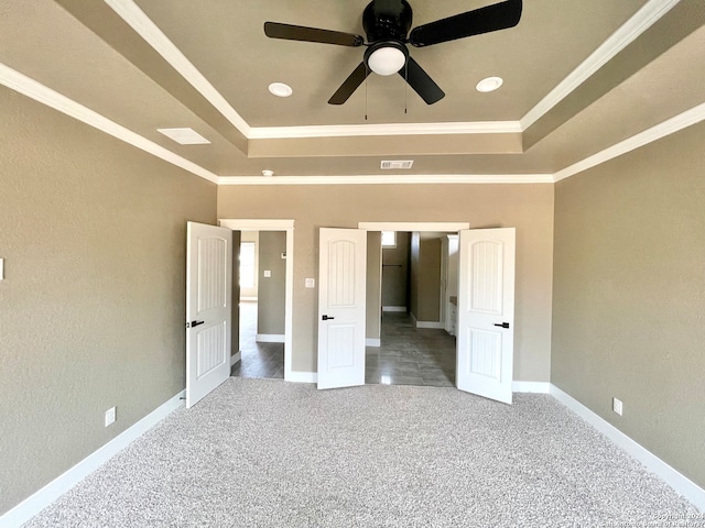 carpeted empty room featuring ceiling fan, ornamental molding, and a tray ceiling