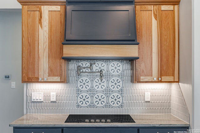 kitchen featuring decorative backsplash, light stone countertops, and black electric cooktop