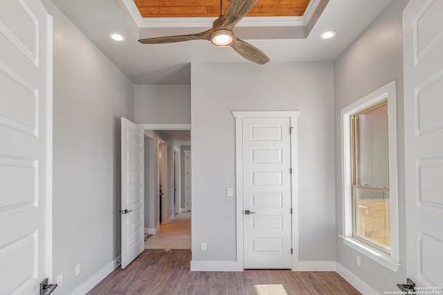 unfurnished bedroom featuring hardwood / wood-style floors, ceiling fan, ornamental molding, and a tray ceiling