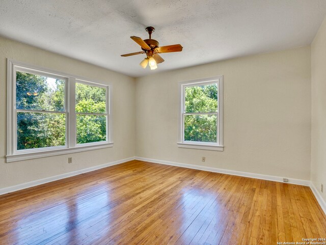 unfurnished room featuring a healthy amount of sunlight, ceiling fan, and light hardwood / wood-style flooring