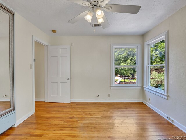 spare room with ceiling fan, a textured ceiling, and light wood-type flooring