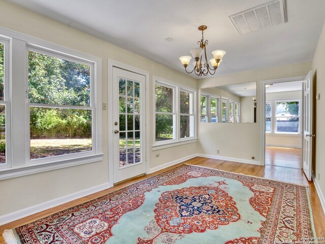 sunroom featuring a healthy amount of sunlight and a chandelier