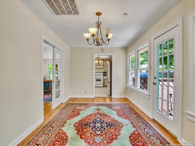 interior space with french doors, an inviting chandelier, and light hardwood / wood-style flooring