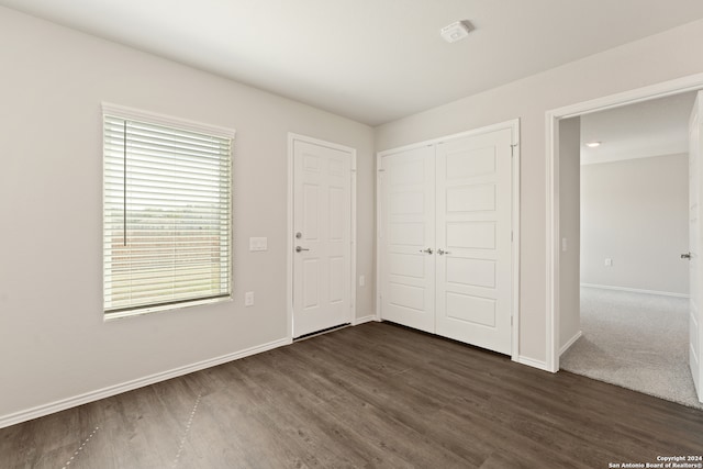 unfurnished bedroom featuring a closet and dark wood-type flooring