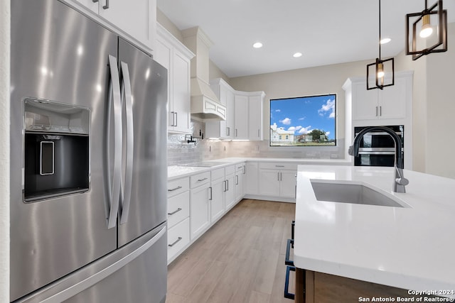 kitchen featuring white cabinetry, decorative light fixtures, tasteful backsplash, light wood-type flooring, and refrigerator