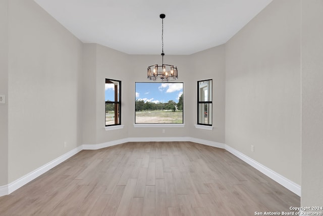 spare room featuring light hardwood / wood-style floors and an inviting chandelier