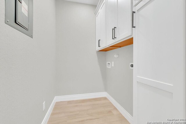 washroom with light hardwood / wood-style floors, cabinets, hookup for an electric dryer, and washer hookup