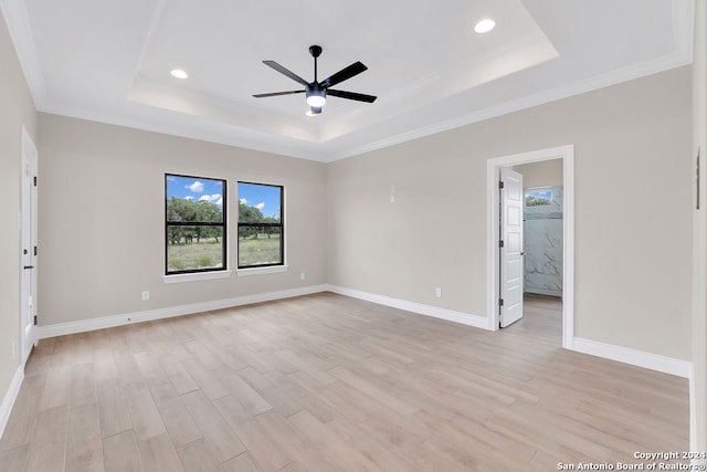 empty room with ceiling fan, light hardwood / wood-style floors, crown molding, and a tray ceiling