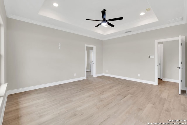 spare room with ornamental molding, ceiling fan, light wood-type flooring, and a tray ceiling