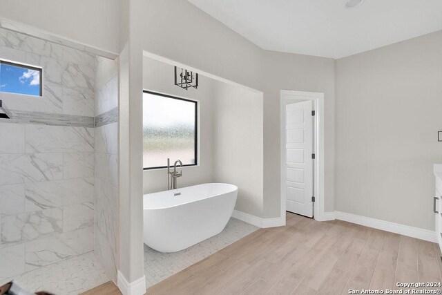 bathroom with hardwood / wood-style floors and a tub to relax in