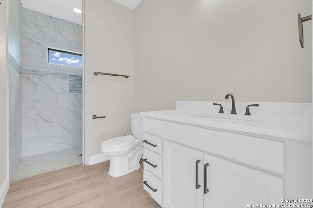 bathroom featuring tiled shower, toilet, and vanity