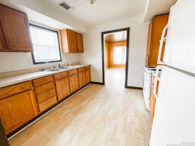 kitchen featuring white appliances, a healthy amount of sunlight, and light hardwood / wood-style flooring