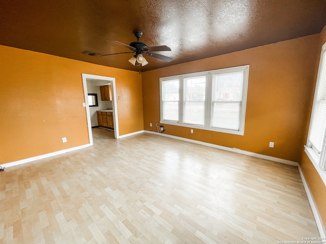 empty room featuring ceiling fan, a textured ceiling, and light hardwood / wood-style floors