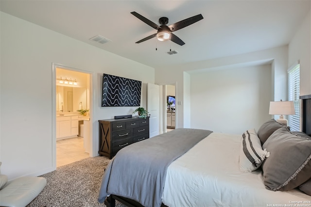 bedroom with light carpet, ensuite bath, and ceiling fan