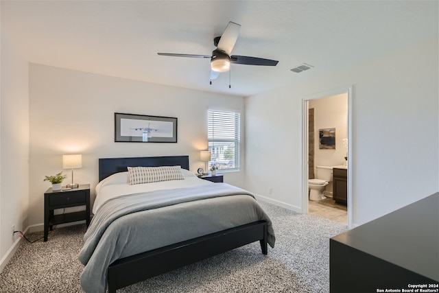 carpeted bedroom with ensuite bath and ceiling fan