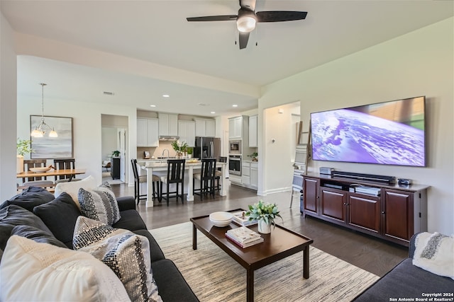 living room with dark hardwood / wood-style floors, ceiling fan with notable chandelier, and sink