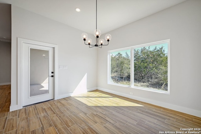 empty room featuring a notable chandelier and light wood-type flooring