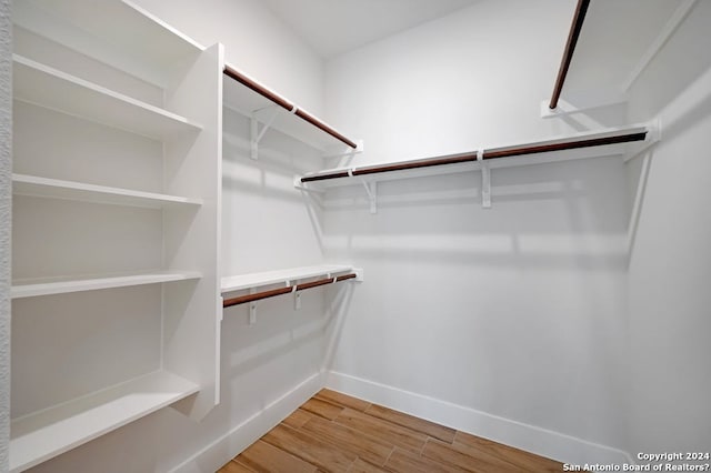 walk in closet with light hardwood / wood-style floors