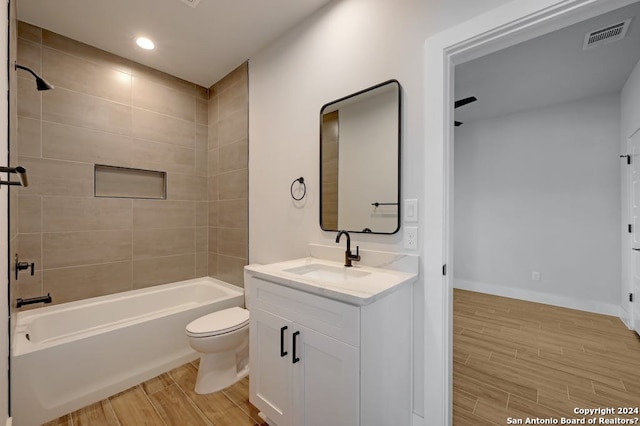 full bathroom with hardwood / wood-style floors, toilet, vanity, and tiled shower / bath