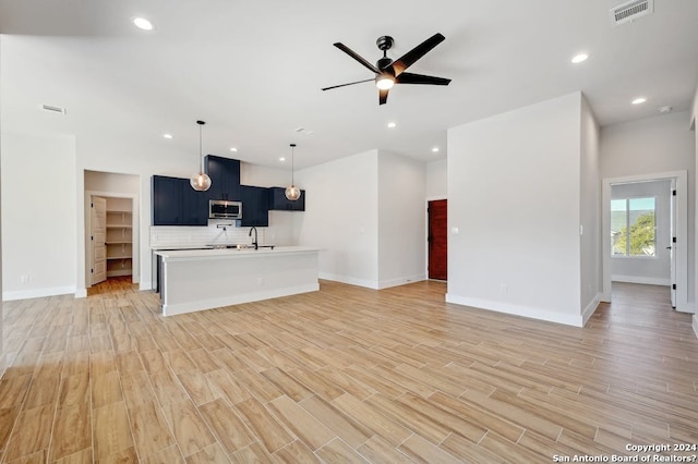 kitchen with pendant lighting, sink, ceiling fan, light hardwood / wood-style flooring, and backsplash