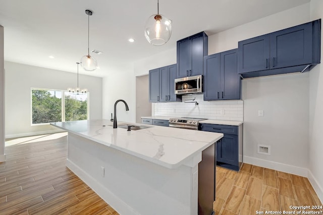 kitchen with appliances with stainless steel finishes, sink, an island with sink, and pendant lighting