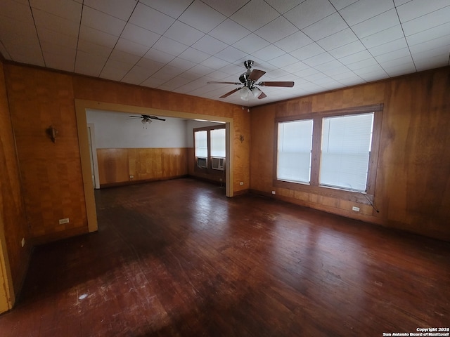 unfurnished room featuring wood walls, ceiling fan, and dark wood-type flooring