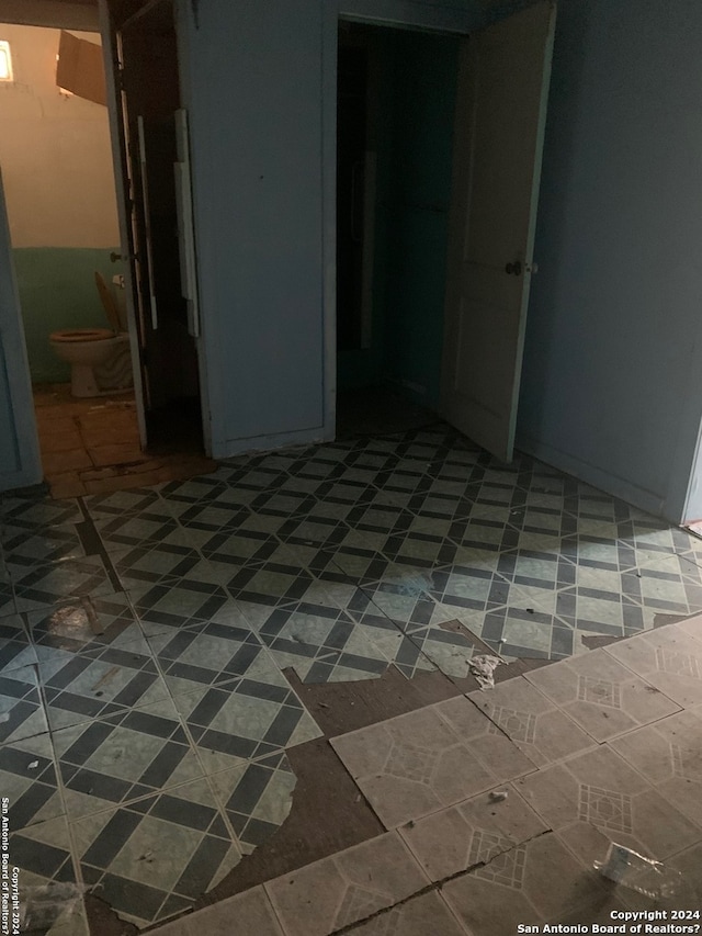 unfurnished bedroom featuring a closet, dark tile floors, and ensuite bathroom