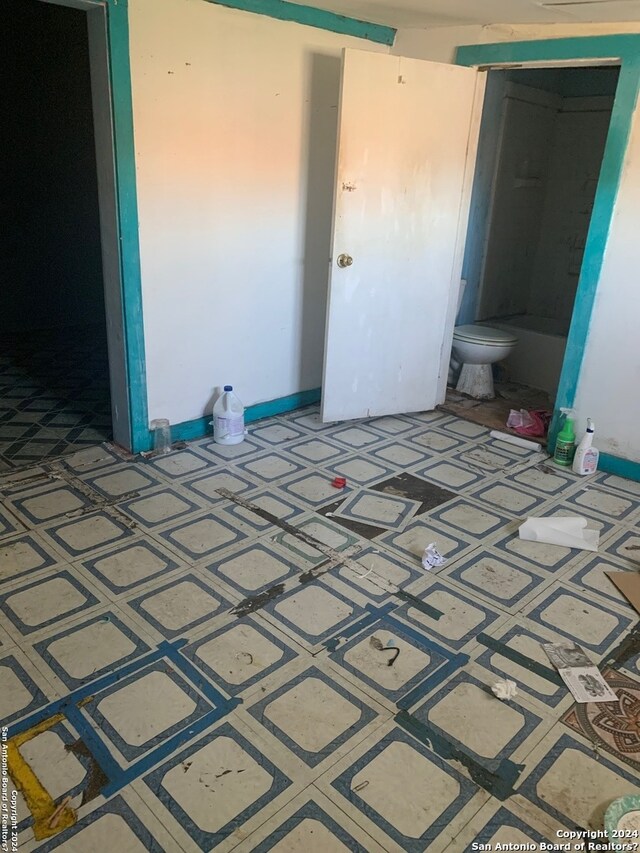 unfurnished bedroom featuring dark tile floors and ensuite bathroom