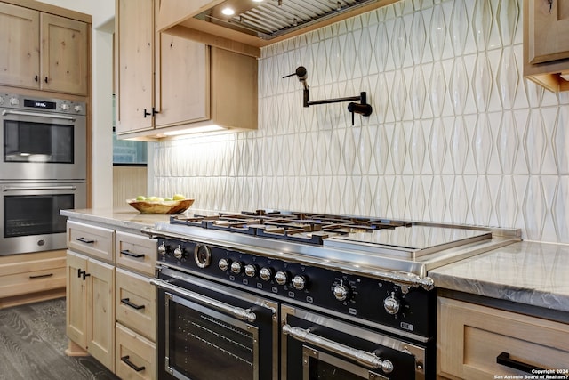 kitchen with double oven, light brown cabinetry, range with two ovens, backsplash, and dark hardwood / wood-style floors