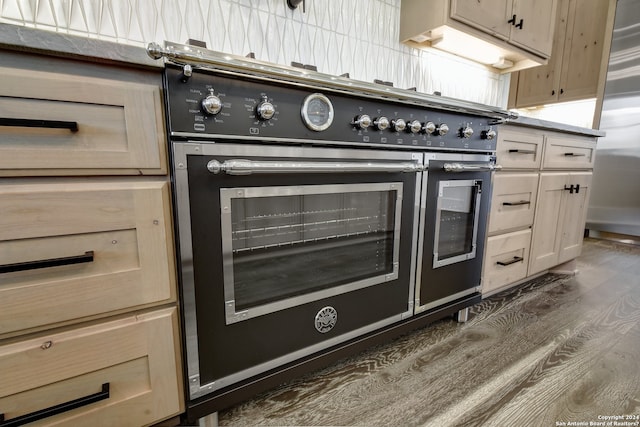 kitchen with range with two ovens, dark hardwood / wood-style floors, stainless steel fridge, and light brown cabinetry