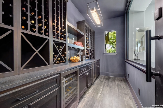 wine cellar with wine cooler, bar area, and light wood-type flooring